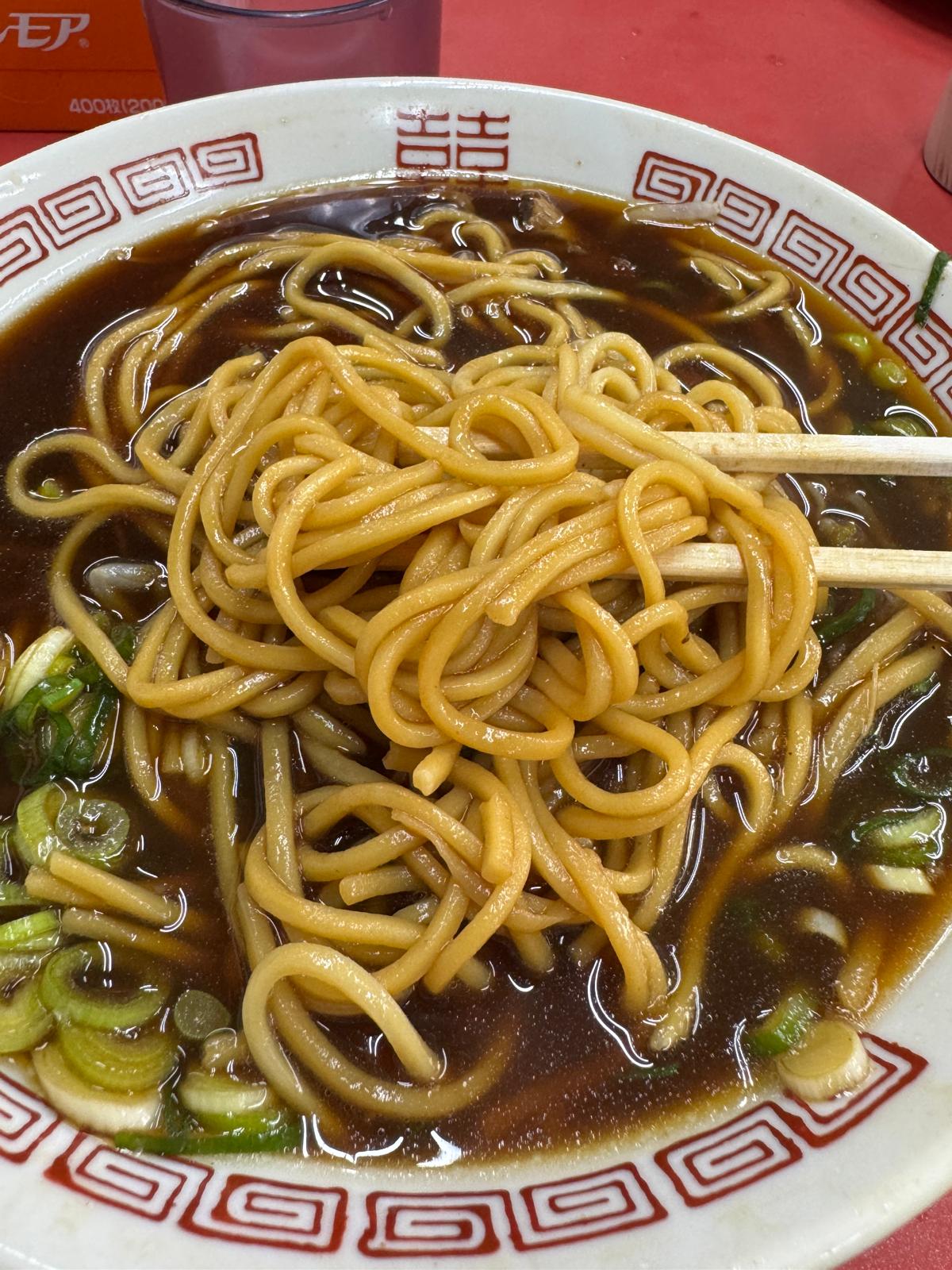 Thick noodles coated in the dark broth at Shinpuku Saikan Honten